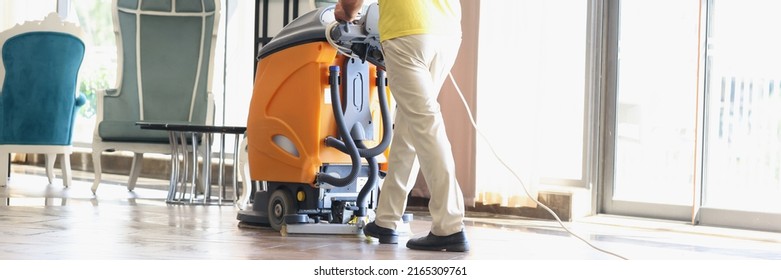 Male Cleaner Cleaning Interior Of Modern Hotel Lobby