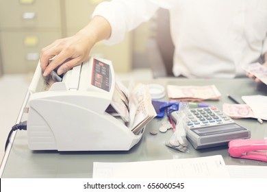 Male Clerk Counting Cash Money By Counting Machine For Customer At Bank Office.