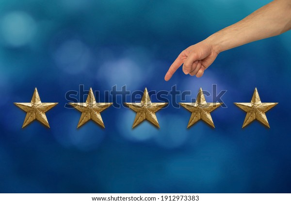 male\
client\'s hand shows five gold foil star on blue background, concept\
of evaluating the result, rating,\
Satisfaction