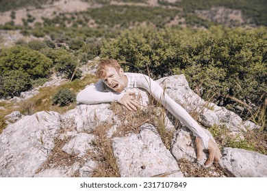 A male climber is barely holding on to a rock without insurance over an abyss. The concept of a prank or an accident in the mountains - Powered by Shutterstock