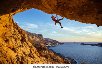 Male climber on overhanging rock against beautiful view of coast below - Shutterstock ID 501632293