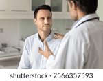 Male clinic patient listening to doctor in hospital office, visiting medical specialist for checkup, getting diagnosis explanation, support, encouraging gesture, treatment and therapy recommendation