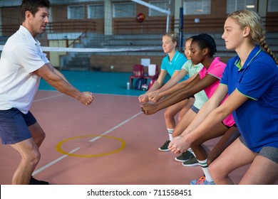 Male coach and female players performing stretching exercise in court - Powered by Shutterstock
