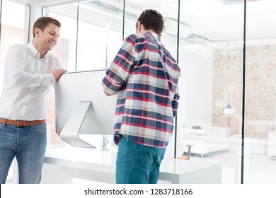 Male Colleagues Carrying Desktop Computer In Office