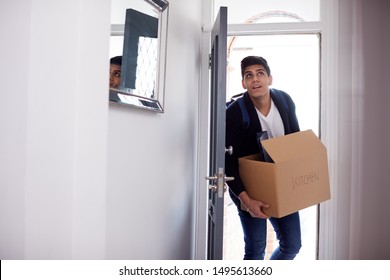 Male College Student Carrying Box Moving Into Accommodation