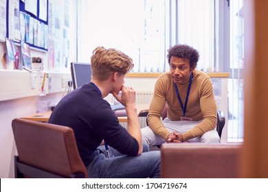 Male College Student Meeting With Campus Counselor Discussing Mental Health Issues