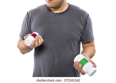 Male Comparing Bottles Of Medicine Or Dietary Supplements.  He Is Holding Two Pill Bottles With Copyspace For Logos.  The Image Can Depict Medicine Versus Generic Drug Brands. 