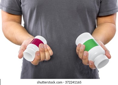 Male Comparing Bottles Of Medicine Or Dietary Supplements.  He Is Holding Two Pill Bottles With Copyspace For Logos.  The Image Can Depict Medicine Versus Generic Drug Brands. 