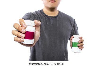 Male Comparing Bottles Of Medicine Or Dietary Supplements.  He Is Holding Two Pill Bottles With Copyspace For Logos.  The Image Can Depict Medicine Versus Generic Drug Brands. 