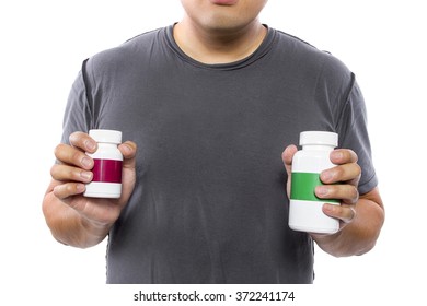 Male Comparing Bottles Of Medicine Or Dietary Supplements.  He Is Holding Two Pill Bottles With Copyspace For Logos.  The Image Can Depict Medicine Versus Generic Drug Brands. 