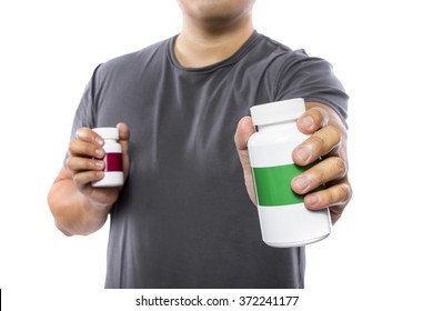 Male Comparing Bottles Of Medicine Or Dietary Supplements.  He Is Holding Two Pill Bottles With Copyspace For Logos.  The Image Can Depict Medicine Versus Generic Drug Brands. 