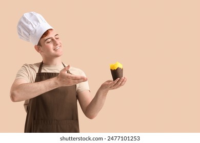 Male confectioner in apron pointing at cupcake molds on beige background - Powered by Shutterstock