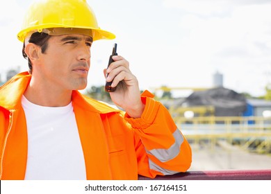 Male Construction Worker Communicating On Two Way Radio At Site