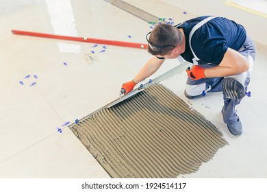 A Male Construction Worker Installs A Large Ceramic Tile	