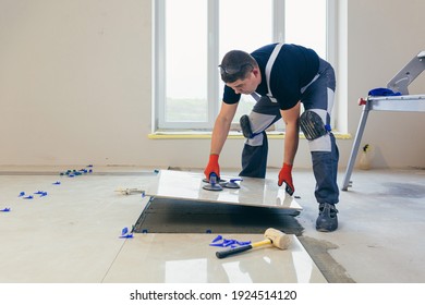 A male construction worker installs a large ceramic tile	