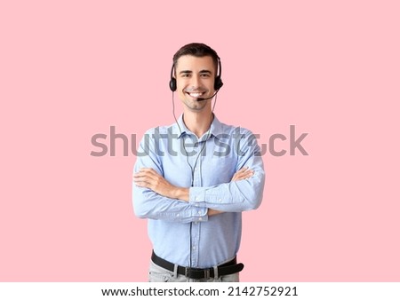 Male consultant of call center with headset on pink background