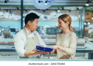 a male consultant in a grocery store advises a woman talking to assistant. seller at vegetable market help customer in supermarket female food girl shop product man choice Asian guy consultor help - Powered by Shutterstock