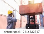 Male container yard worker working, control container boxes on forklift truck before loading at commercial dock site. Male people worker work at cargo freight ship