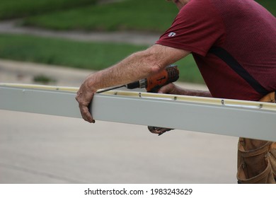 Male Contractor Preparing Seamless Gutter To Be Installed On A Residential Building