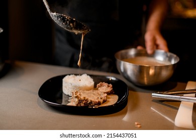 Male Cook Accurate Pouring Sauce Over A Slice Of Fried Meat On A Plate With Rice Dish