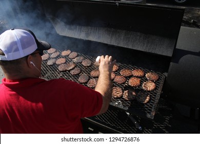 Male Cook Cooking Burgers In Large Grill. Tailgate Party Chef Grilling Outdoors With Family And Friends. - Image