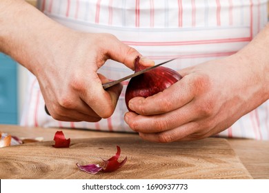 A male cook peels onions with a knife in close-up. The concept of organic cooking.