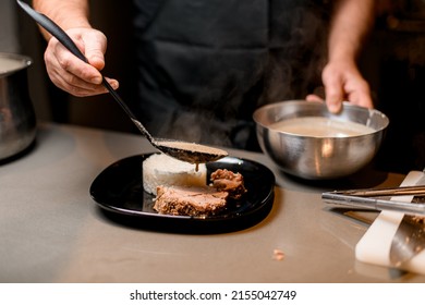 Male Cook Pouring Sauce Over A Slice Of Fried Meat On A Plate With Rice Dish