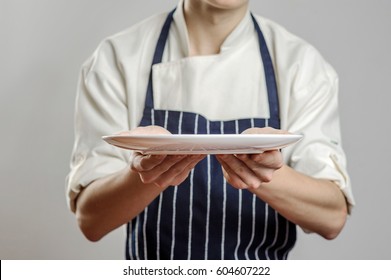 Male cook in uniform holding an empty tray