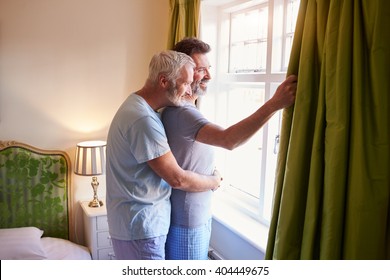 Male couple embrace looking out of their hotel room window - Powered by Shutterstock