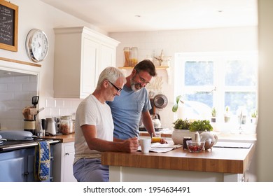 Male Couple In Their Kitchen Reading A Paper In The Morning