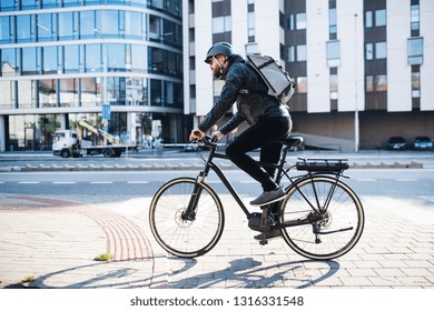 Male courier with bicycle delivering packages in city. Copy space. - Shutterstock ID 1316331548