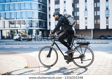 Male courier with bicycle delivering packages in city. Copy space.