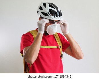 A male Courier in a protective gloves,  mask and Bicycle helmet wears sunglasses. - Powered by Shutterstock