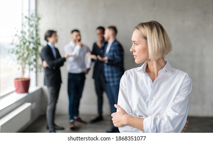 Male Coworkers Whispering Behind Back Of Unhappy Businesswoman Spreading Rumors And Gossips Standing In Modern Office. Sexism And Bullying Problem At Workplace Concept. Selective Focus - Shutterstock ID 1868351077