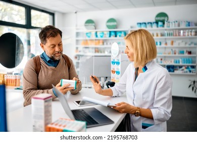 Male customer consulting with is pharmacist while buying prescription medicine in a pharmacy.  - Powered by Shutterstock