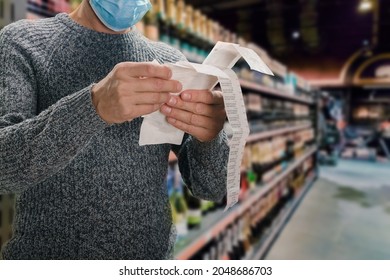 Male customer doing grocery shopping at supermarket and feeling confused by bill