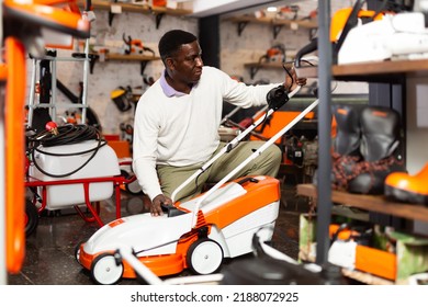 Male Customer Examining Lawnmowers In Garden Equipment Shop