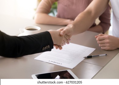 Male customer and female insurance broker shaking hands, couple and real estate agent handshaking after signing document, close up of making deal with satisfied clients, contract with a firm 
