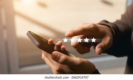 A male customer gives a five-star rating on their smartphone, satisfaction, customer service experience. Service Rating Reviews and Satisfaction Survey Concept.
