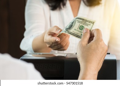  
Male Customer Paying 100 Dollar Bill  To A Woman Cashier At Register Counter .Pay With Cash At Retail Shop.