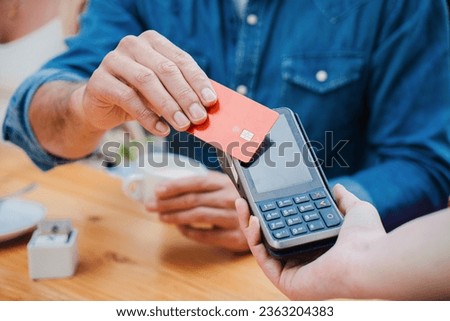 Male customer paying a bill with a contactless credit card in a restaurant. Close up portrait of a man hand holding a creditcard and giving a payment transaction to the cashier. High quality photo