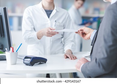 Male customer at the pharmacy, he is giving a prescription to the pharmacist, healthcare concept - Powered by Shutterstock