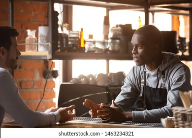 Male Customer Stand Near Counter Talk With African American Barista Or Waiter, Millennial Man Client Speak With Black Barmen Make Order In Bar Or Restaurant, Place Manager Have Conversation With Staff