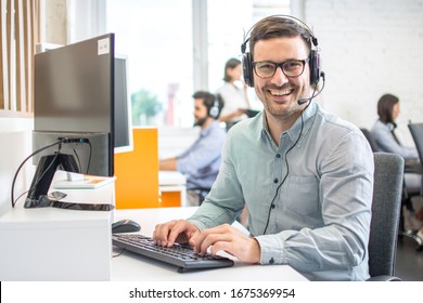 Male Customer Support Phone Operator With Headset Working In Call Centre. Group Of Sales Agent Working In Office.