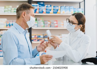 Male customer visitor giving medical prescription to female pharmacist in medical mask against coronavirus, while druggist advising new remedy pills antibiotics - Powered by Shutterstock