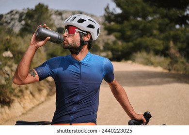 A male cyclist in cycling attire and a helmet is drinking water from a sports bottle during training.
 - Powered by Shutterstock