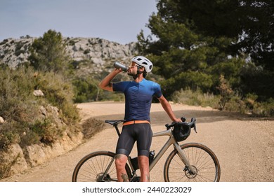 A male cyclist in cycling attire and a helmet is drinking water from a sports bottle during training.
 - Powered by Shutterstock