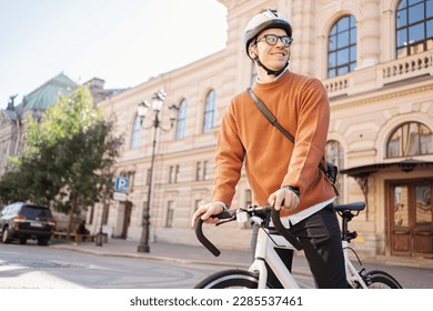 A male cyclist in a helmet is a teenager freelancer going to the office for work Monday on a bicycle eco transport in the city. - Powered by Shutterstock