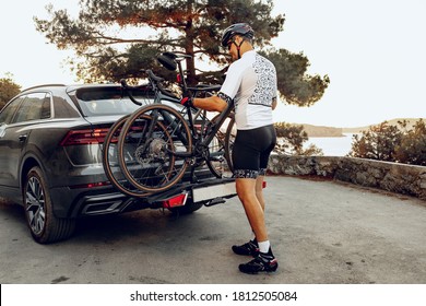 Male cyclist loading his bicycle on a rack of his crossover car