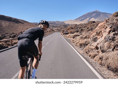 Male cyclist pedaling on road with view on mountain Teide volcano,Tenerife,Canary Islands,Spain. Sportsman training hard on bicycle outdoors.Sport motivation.Cycling training outdoors.Hipster cyclist. - Powered by Shutterstock